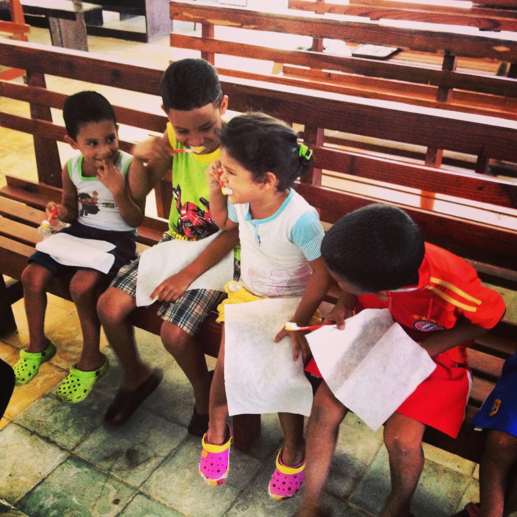 Children brushing their teeth together as a group