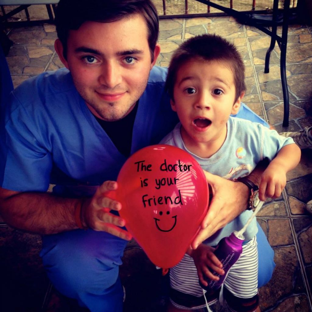 A volunteer doctor holding a child and smiling for a photo