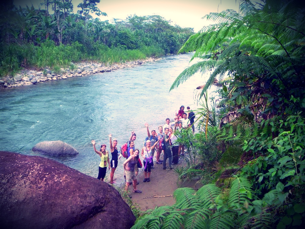 A group of people by the water waving for a photo