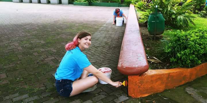 Volunteer helping paint a curb
