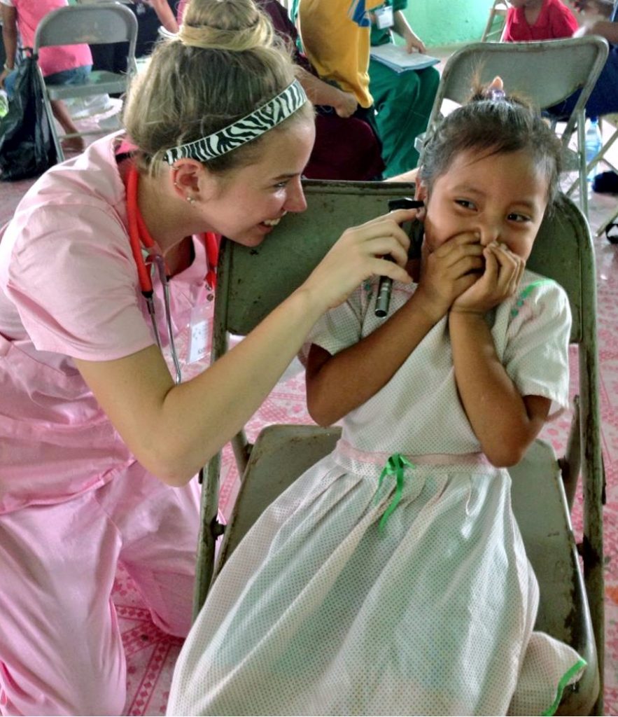 A nurse checking the ear of a child