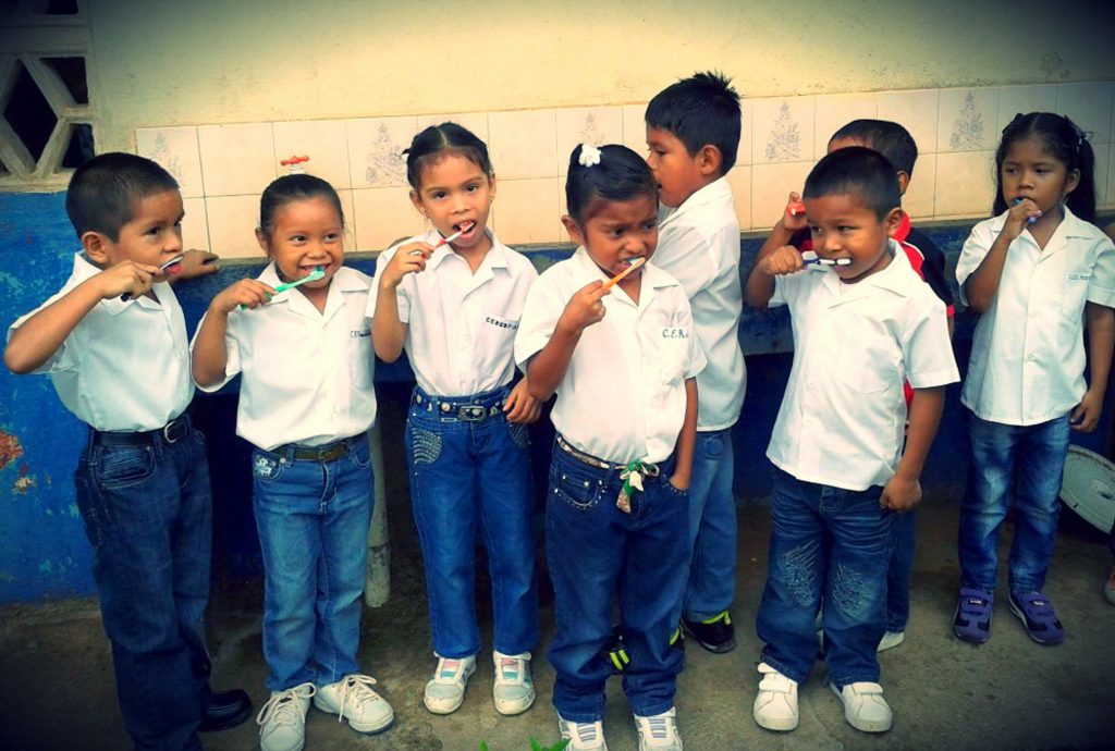 A group of small children learning to brushing their teeth