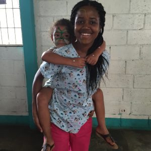 A nurse giving a small child a piggy back ride