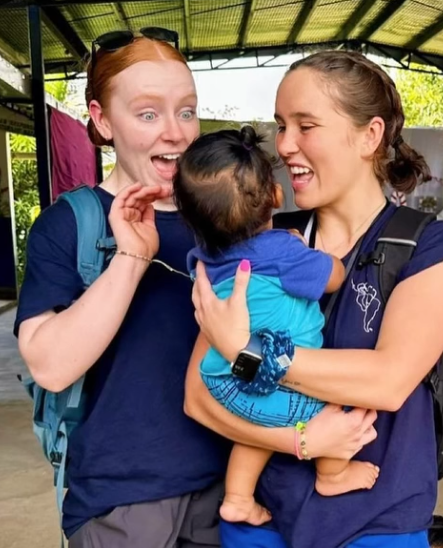Two volunteers making sweet faces to a baby