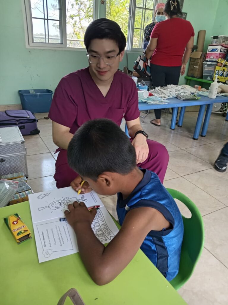 A volunteer teacher watching a child color in a coloring book