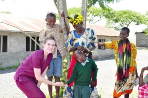 A ISL volunteer smiling and holding a small boys hand in Tanzania